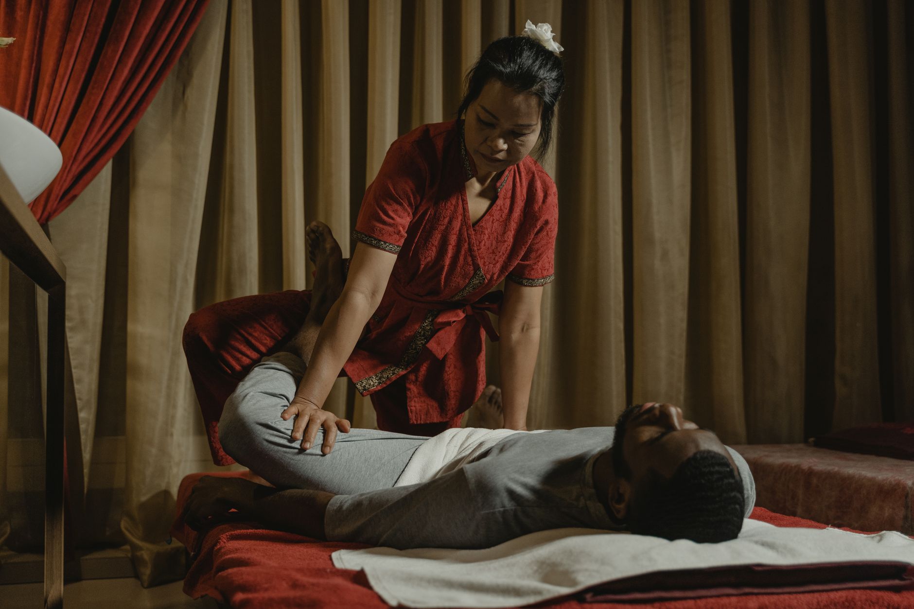 Therapist guiding an assisted leg stretch for a fully clothed client during a Thai yoga massage
