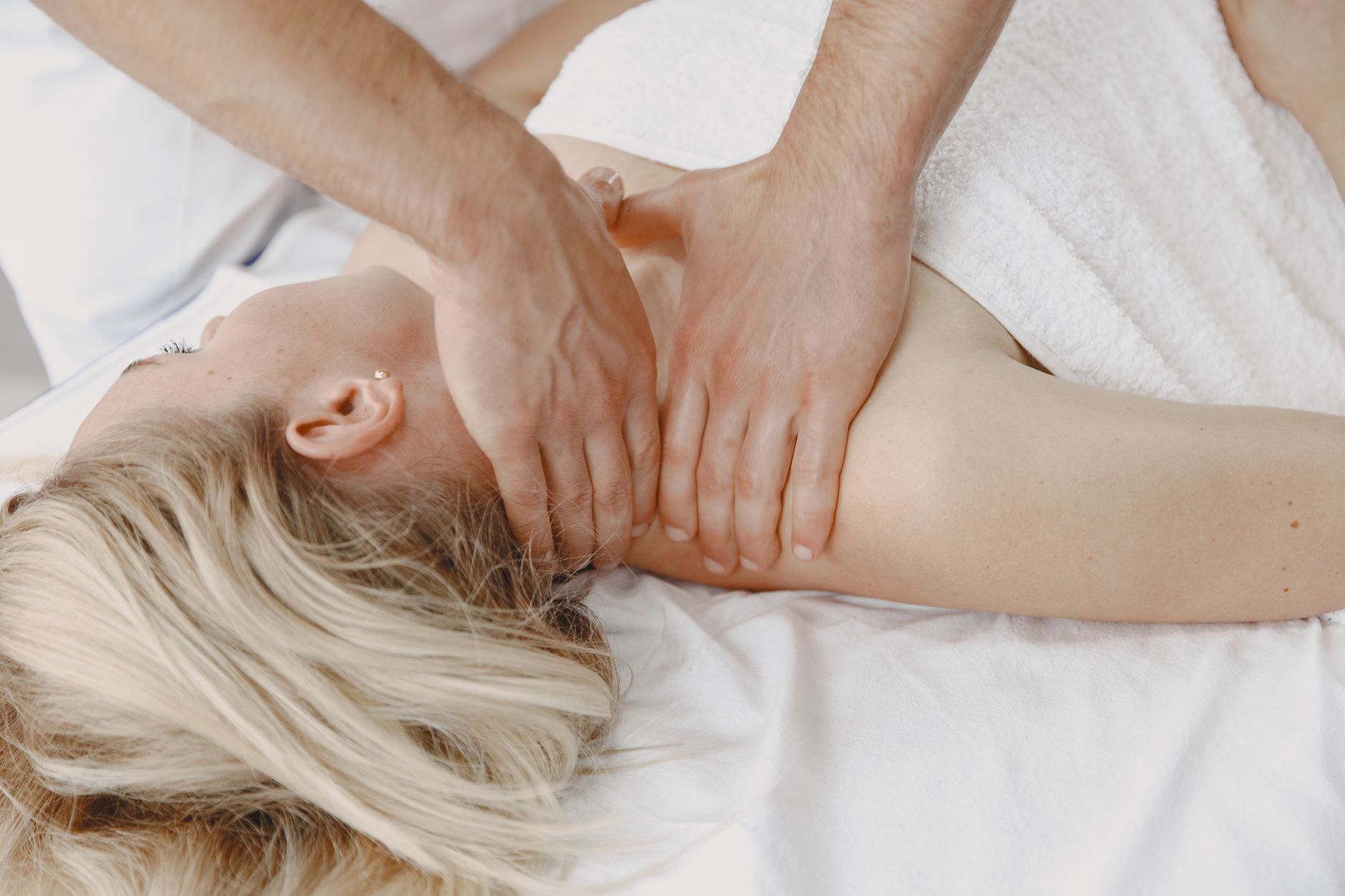 Therapist applying focused finger pressure to a tight spot in a client's neck and shoulder